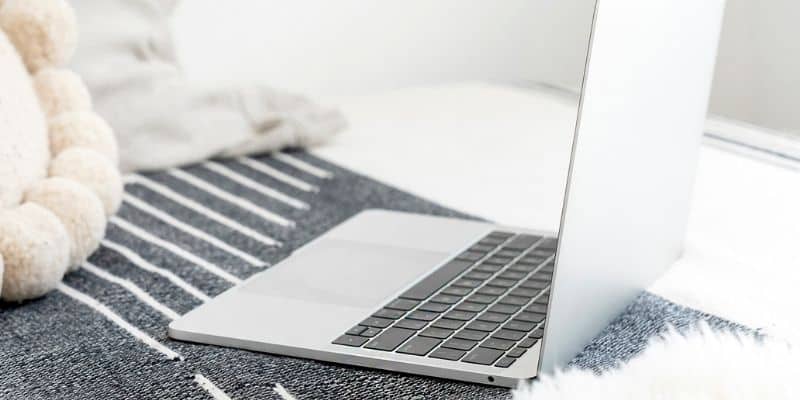 laptop computer on bed with gray blanket