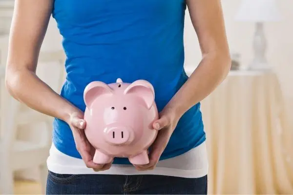 woman in blue shirt holding piggy bank. frugal living tips to save money