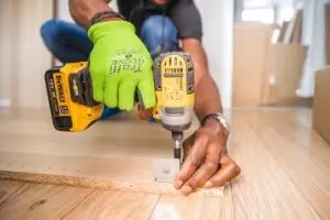 Man using power drill on floor. learn some DIY as part of living frugally